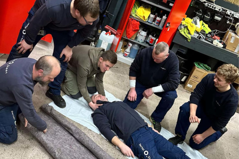 Bildet viser fem personer som legger en skadet person på båre. Dette er en øvelse for industrivernet.